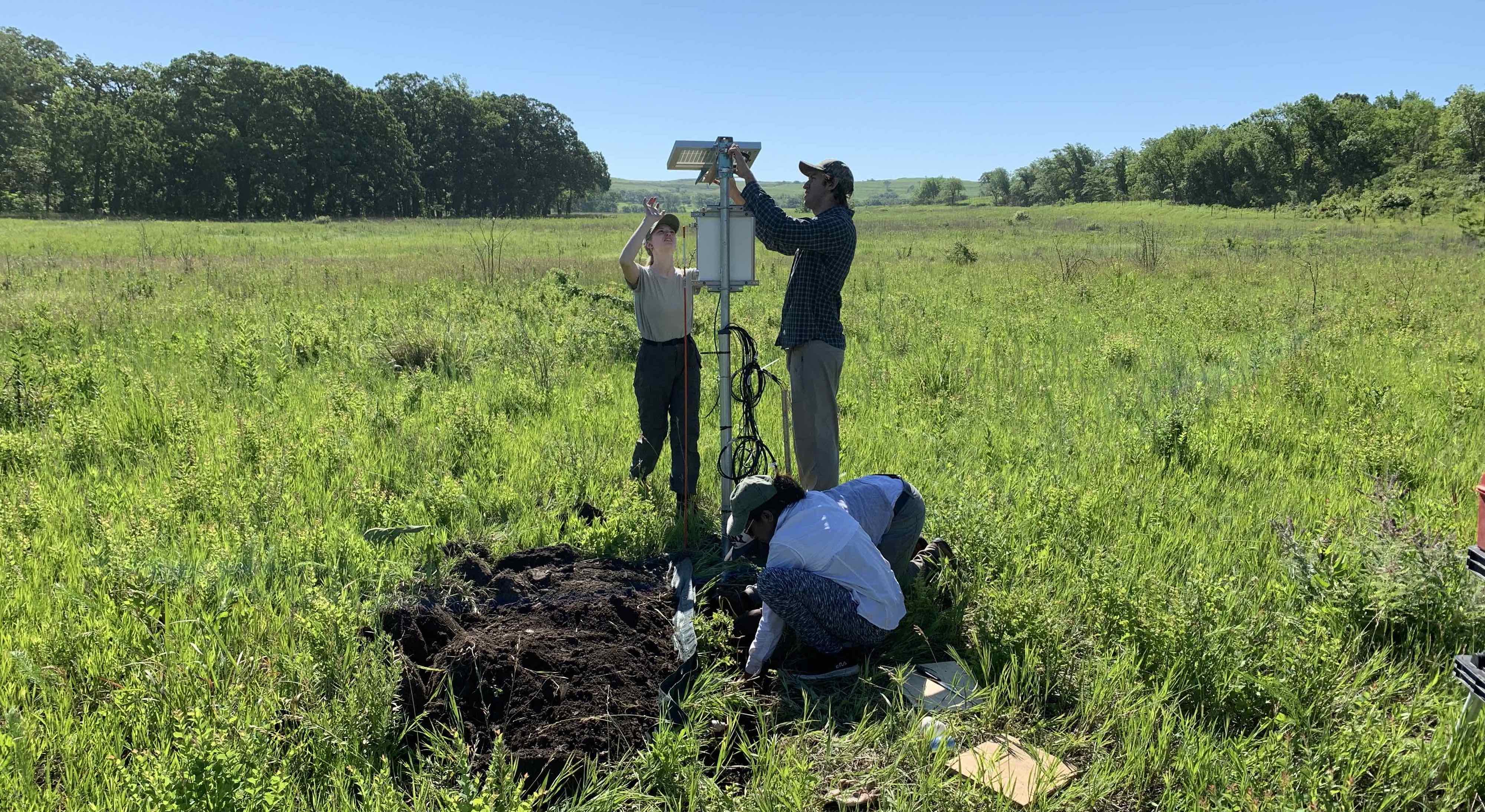 Researchers installing a soil moisture monitoring station in a tallgrass prairie field.